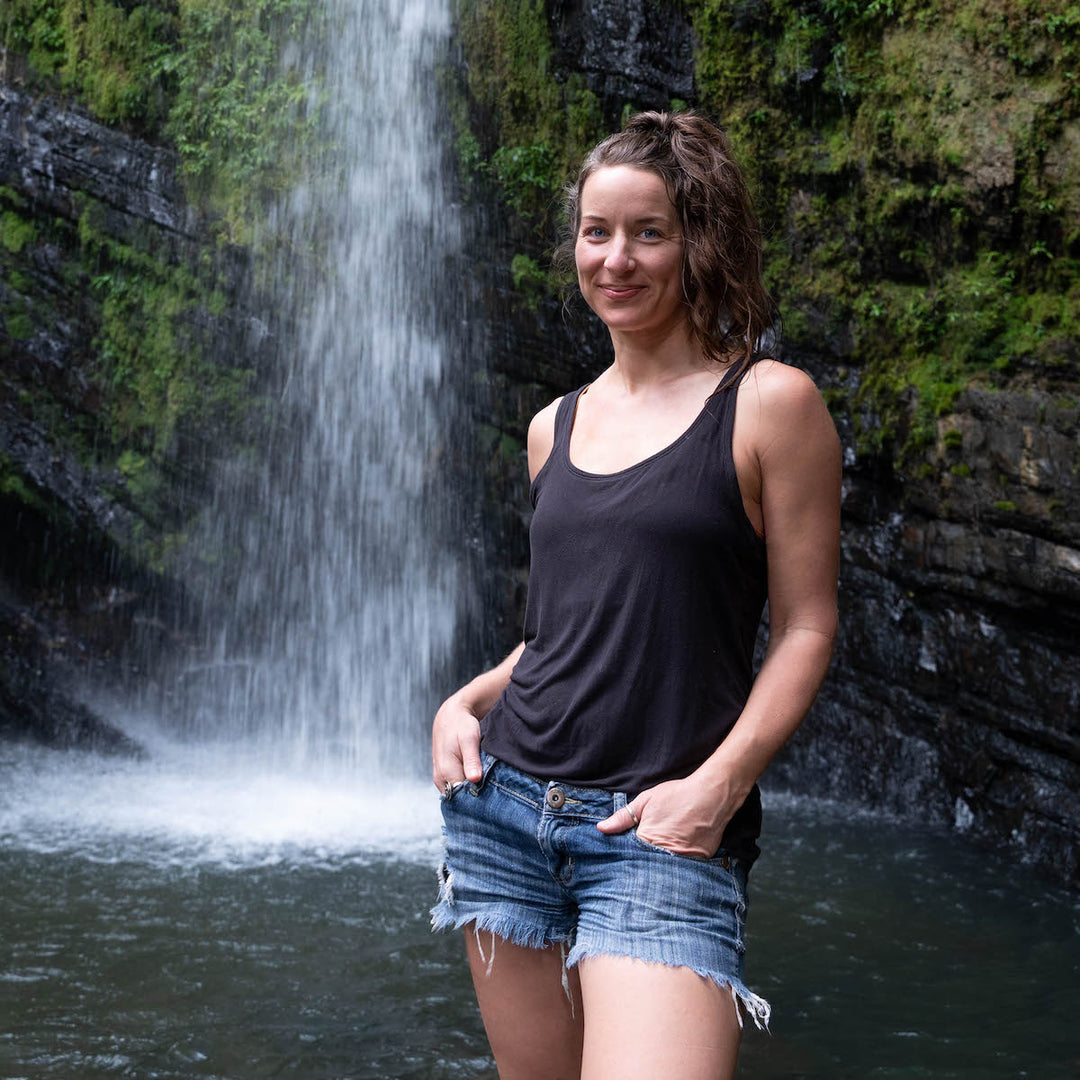 Karie, Co-founder of CinderBird, standing in front of a jungle waterfall
