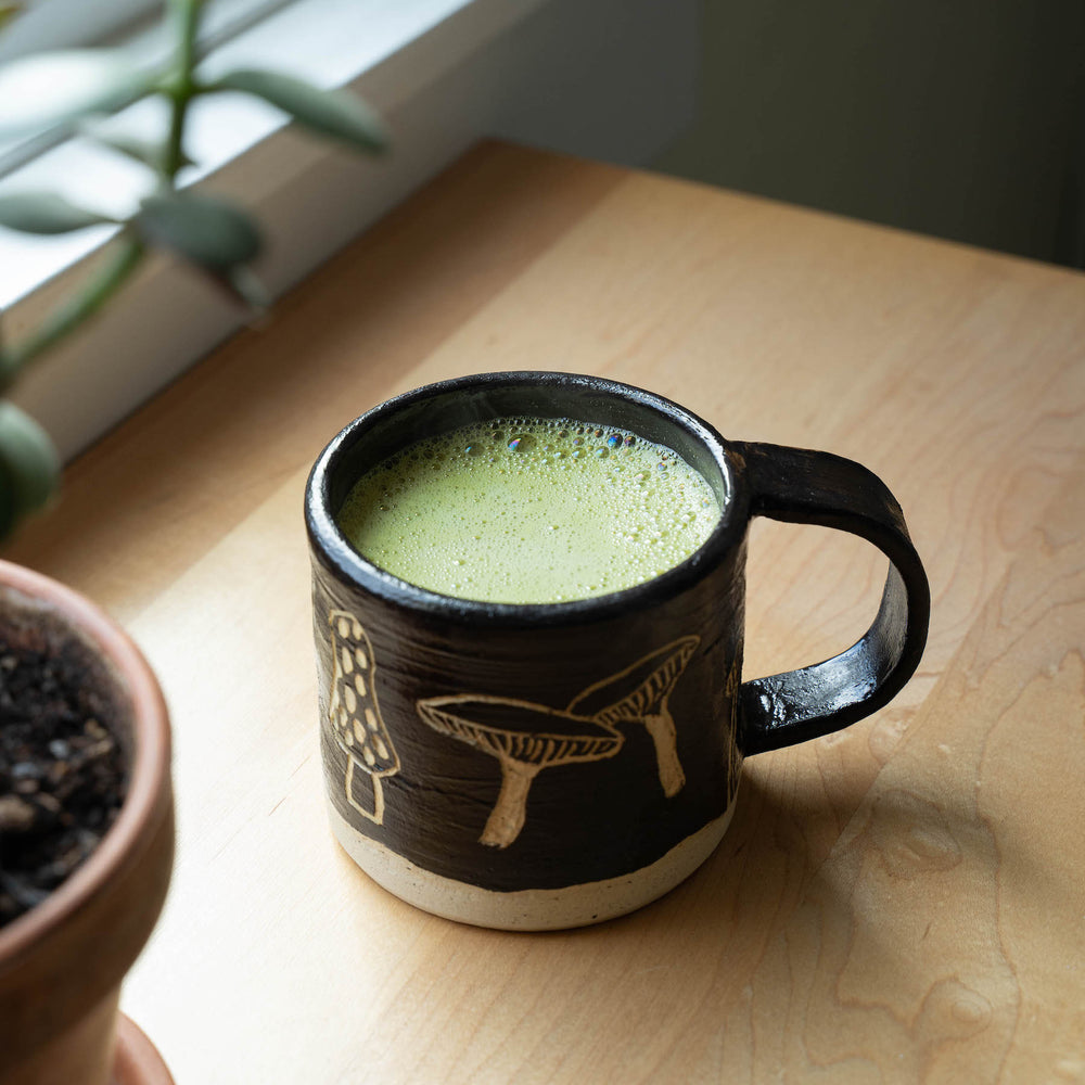 A frothy matcha latte in a mushroom mug